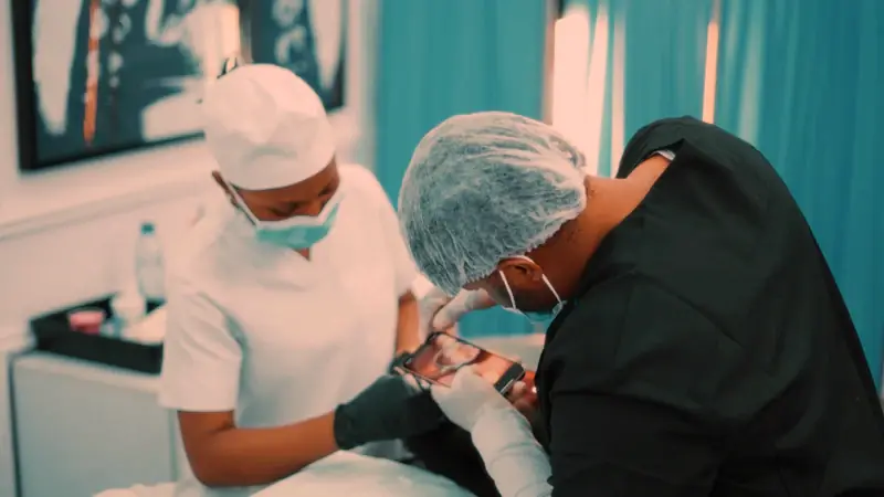 Two dental staff in masks cleaning a patient's teeth