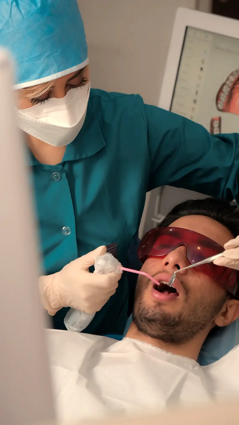 A patient in protective glasses in the dental chair while a dentist works on a tooth
