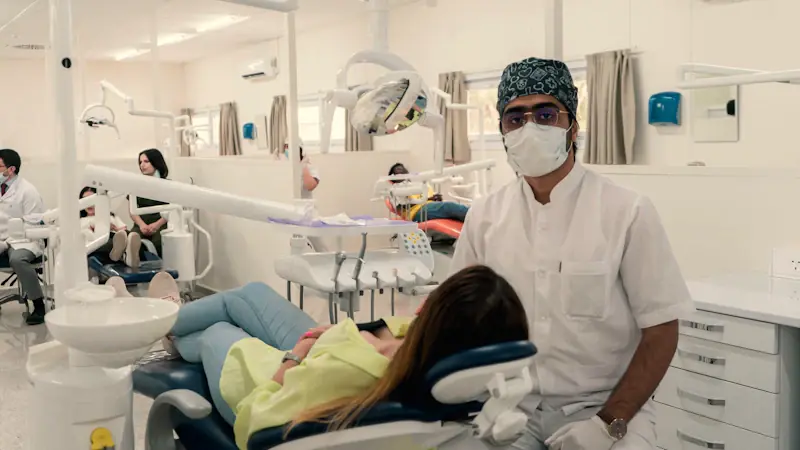 A dentist in a mask beside a patient lying back in the dental chair